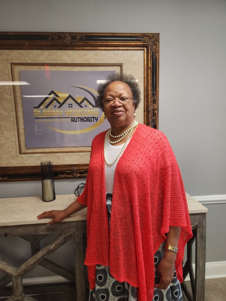 Jeanette Henderson standing in front of Albany HA Logo